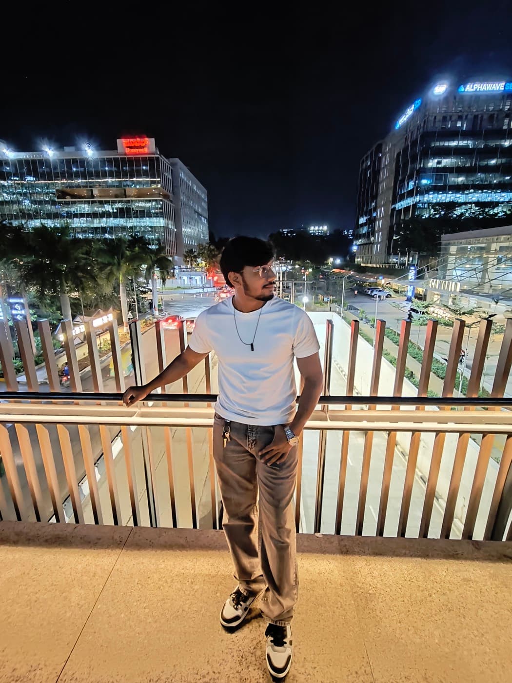 Aftab on a walkway at night, with a lit tech park behind him.