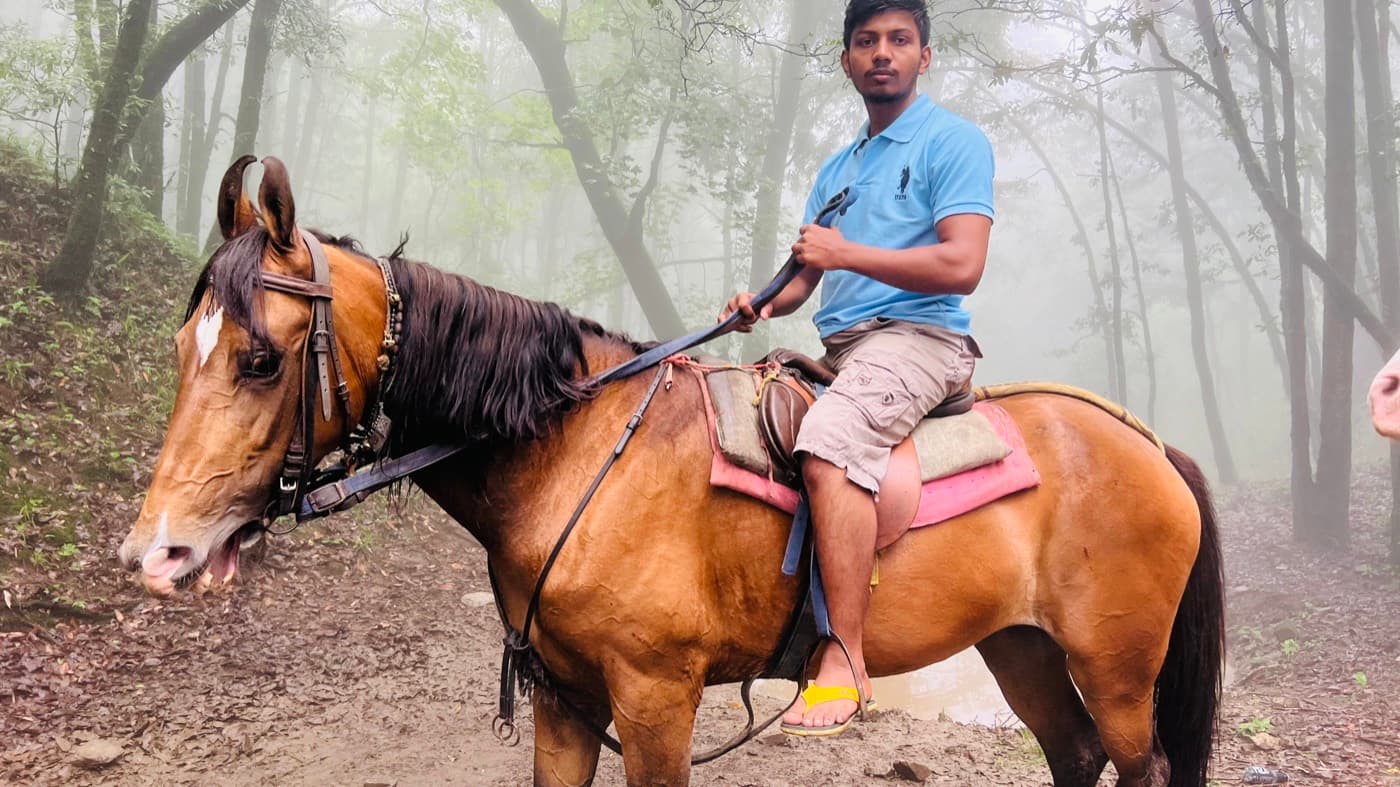 Aftab on horseback on a misty hill trail.